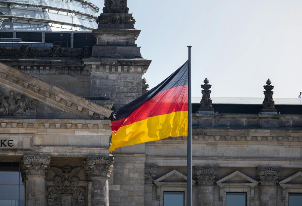German flag waves at the iconic Reichstag building in Berlin, symbolizing national pride.