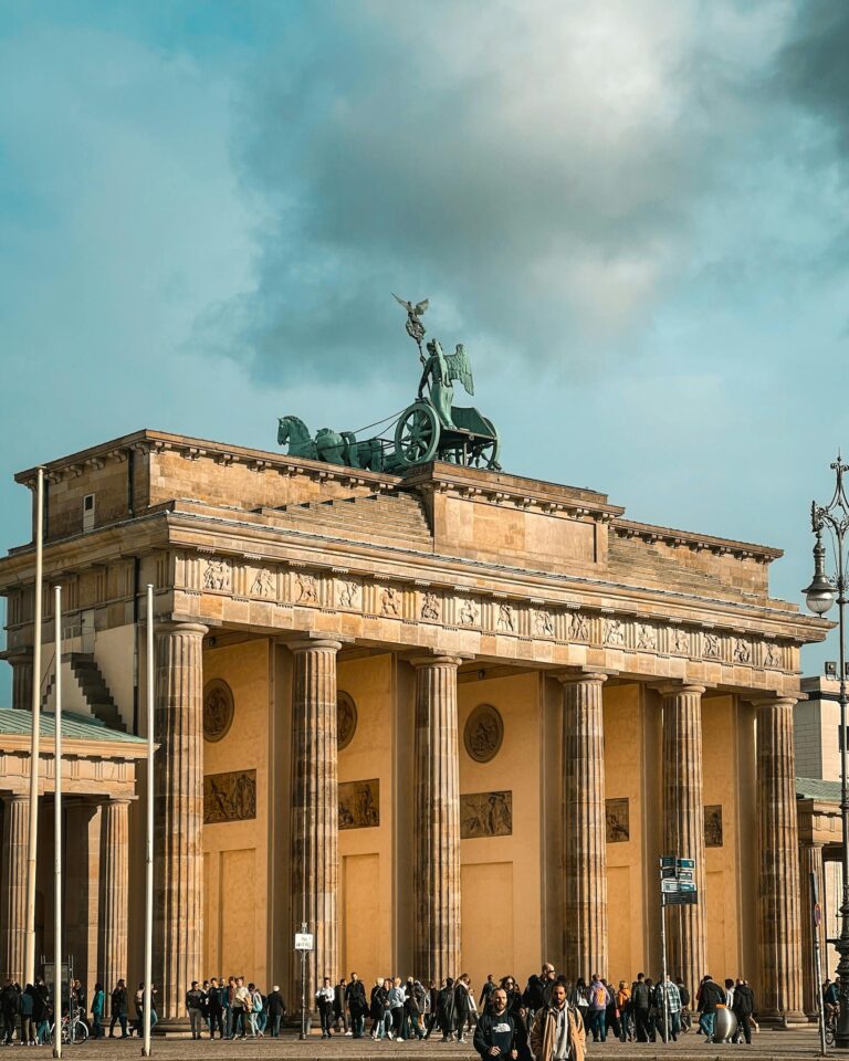 Iconic Brandenburg Gate in Berlin with a cloudy sky, a symbol of German history and architecture.