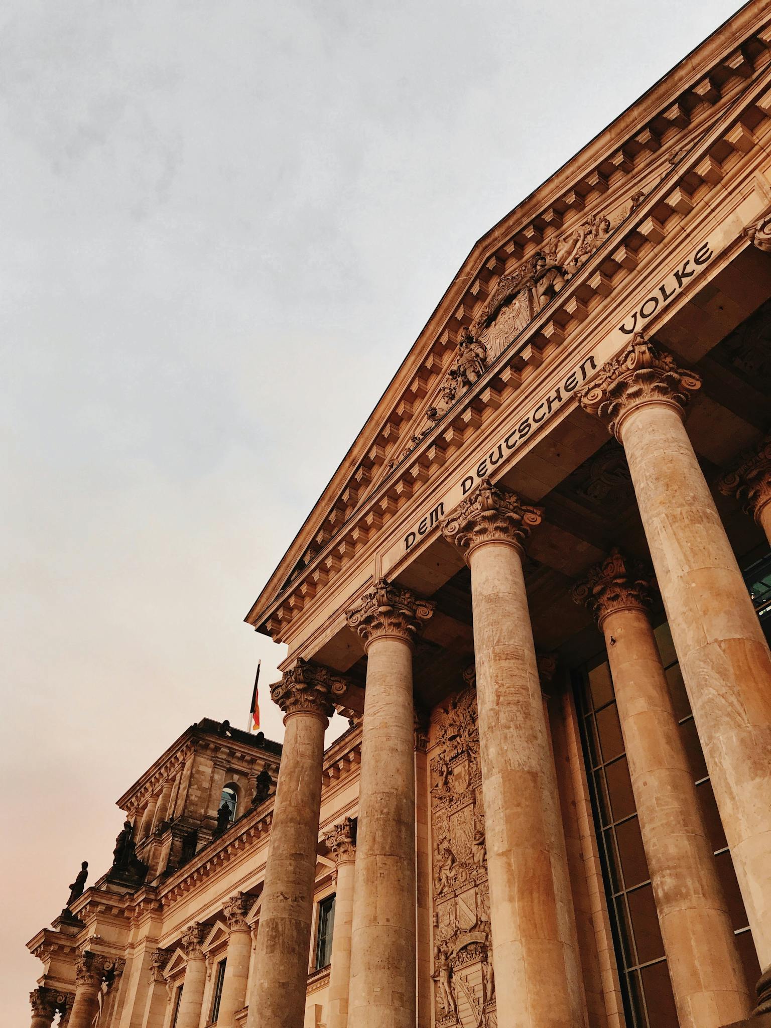 Low angle shot of Reichstag Building facade in Berlin, showcasing majestic columns at sunset.