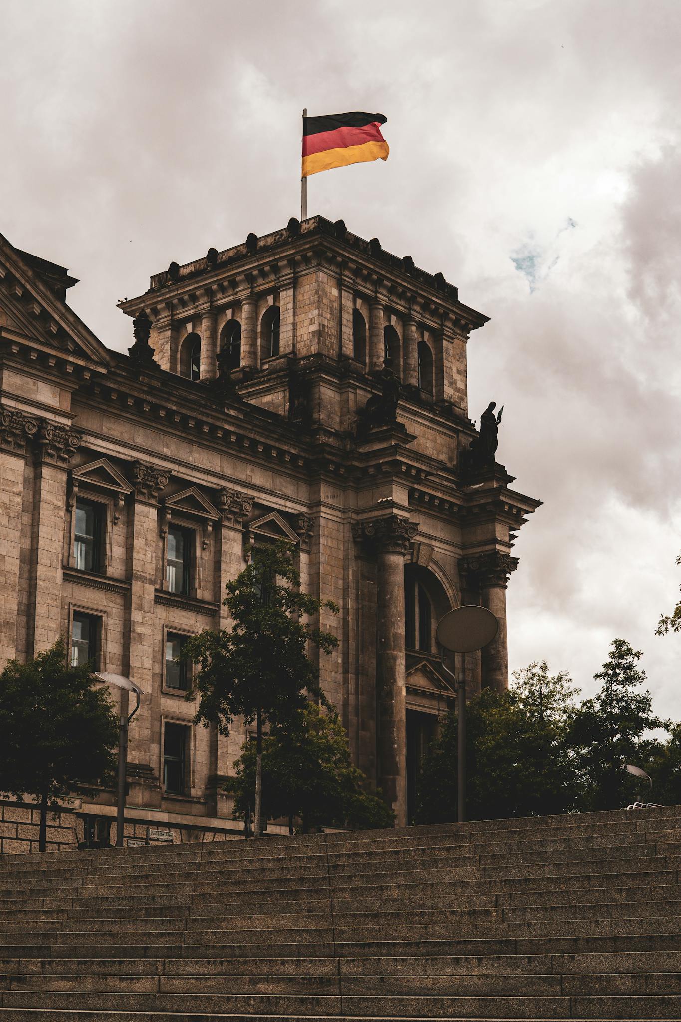 View of the historic Reichstag building in Berlin, Germany, featuring Renaissance architecture and the German flag waving above.